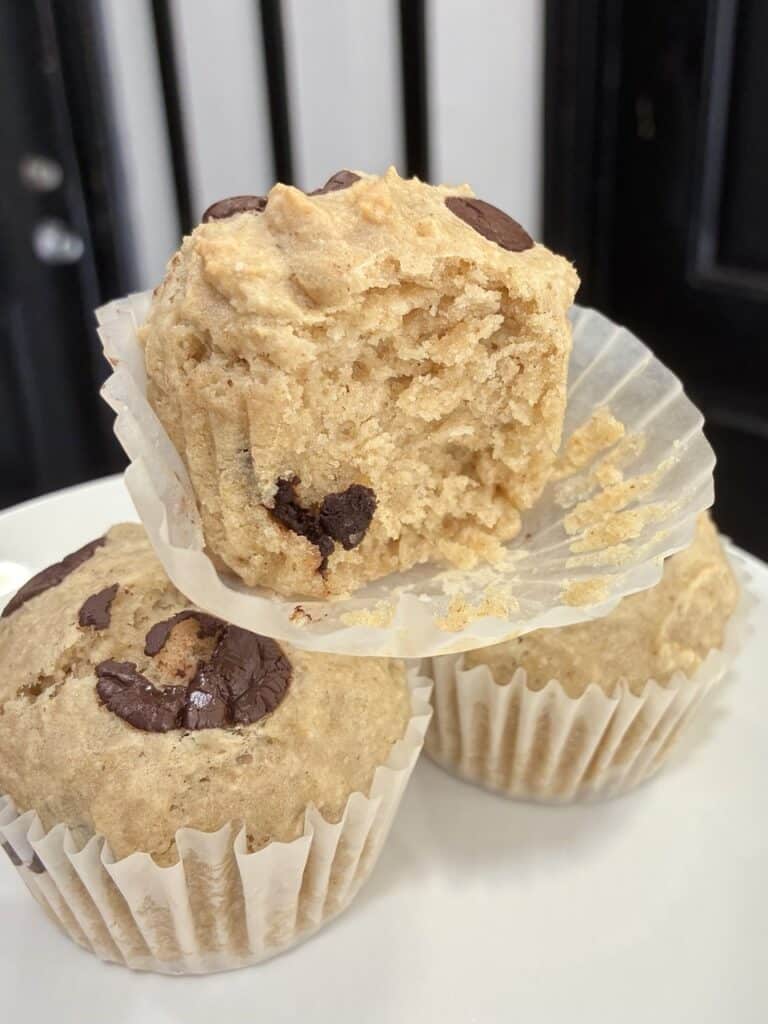 A close up of the soft and fluffy interior texture of an oat flour chocolate chip muffin, showing the moist crumb and melted chocolate chips.