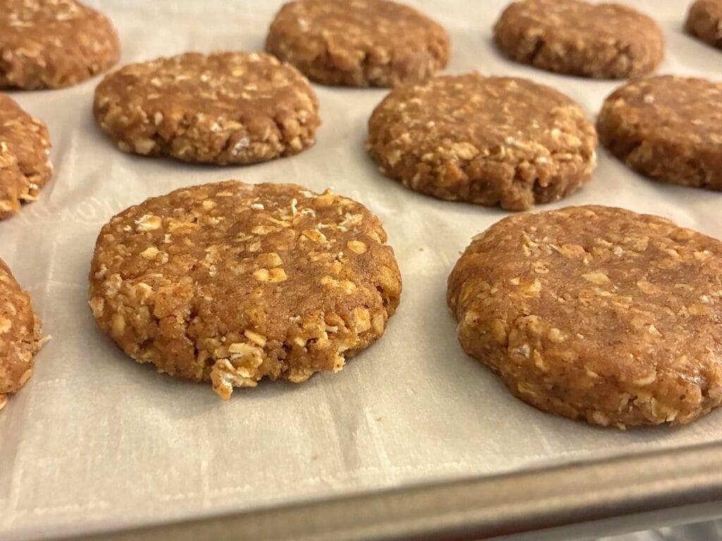 aw cookie dough rounds stamped onto parchment paper with a 1.5-inch scoop and flattened into half-inch thick discs.