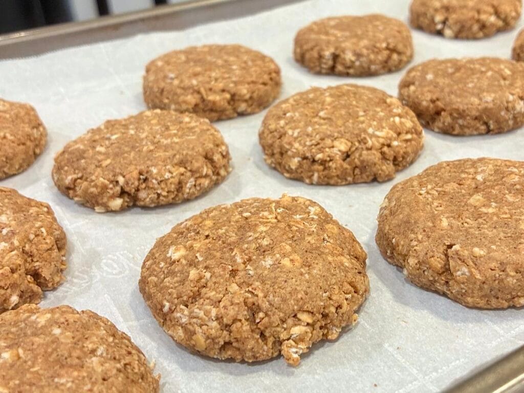 Golden brown soft-baked oatmeal cookies cooling on a parchment paper lined baking sheet fresh out of the oven.