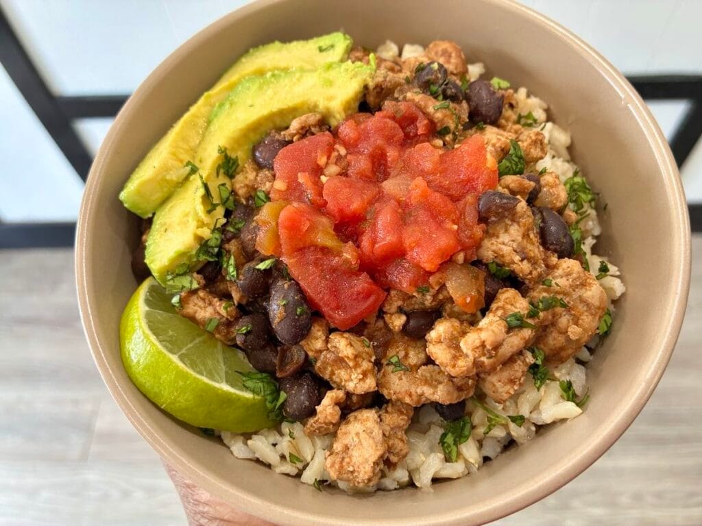 Turkey and black bean taco skillet bowl topped with avocado slices lime and fresh cilantro