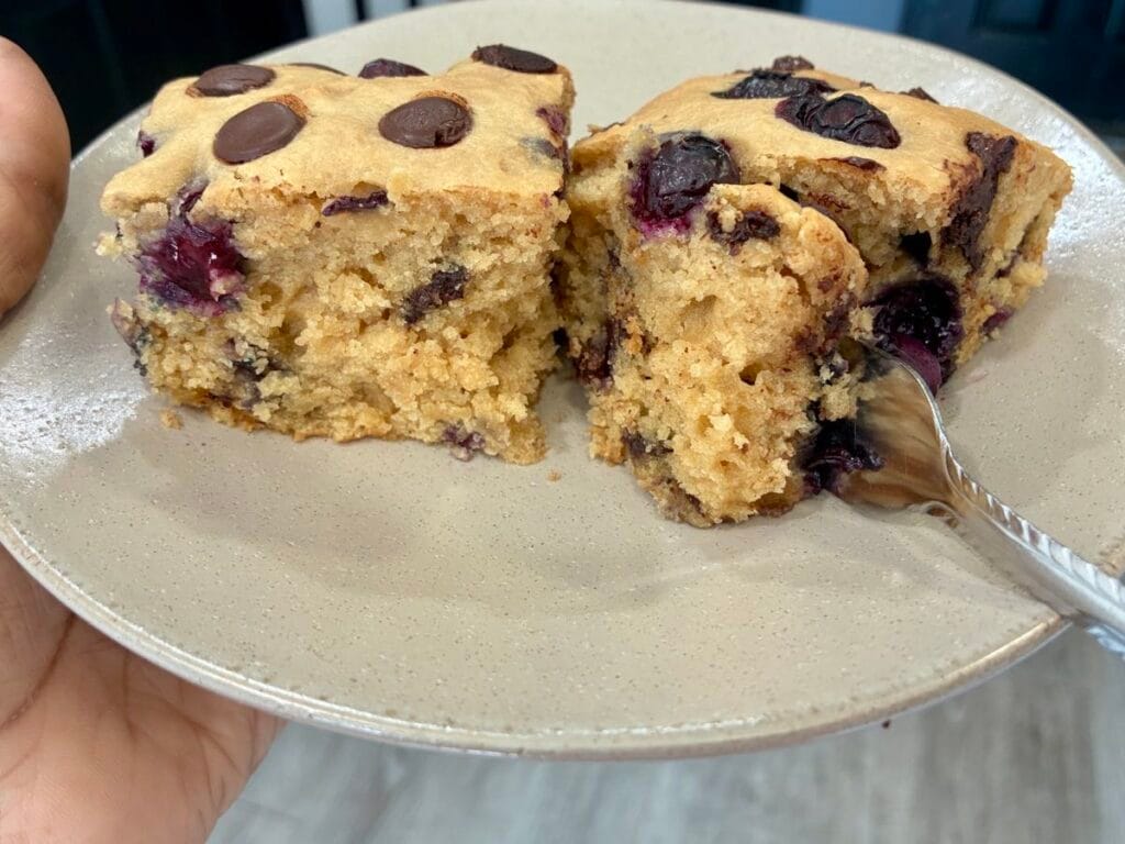 A couple of slices of a freshly baked blueberry chocolate chip snack cake on a plate