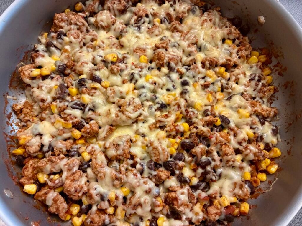 A completed fifteen minute turkey taco skillet with a thick, bubbling layer of melted cheese straight off the stove.