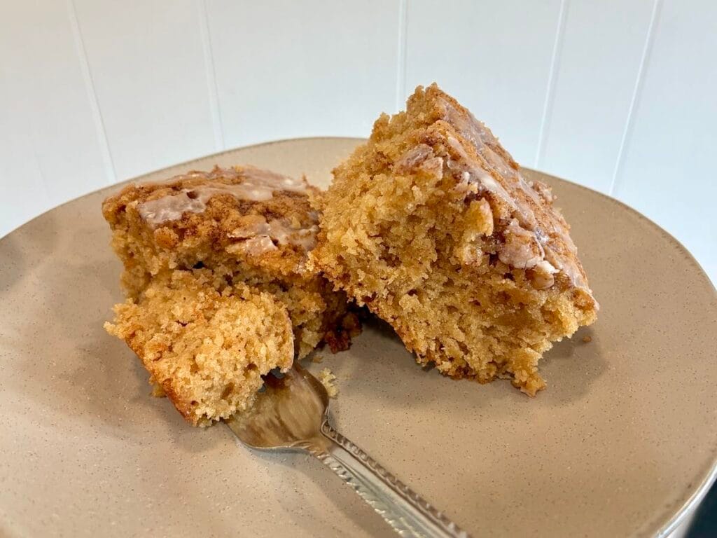 One-Bowl Cinnamon Swirl Snack Cake (Egg-Free Recipe) 5 A close-up view of a dessert fork cutting into a slice of glazed cinnamon snack cake to show the soft, fluffy interior crumb.