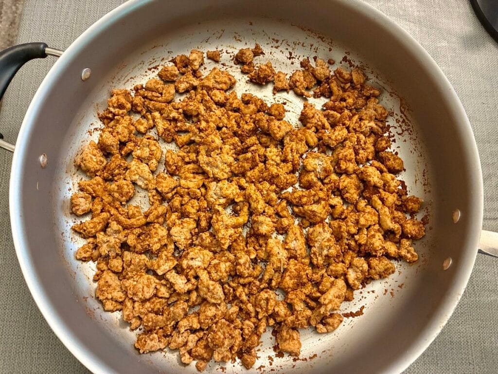 Seasoned ground turkey mixture simmering with homemade taco seasoning in a large skillet before adding casserole ingredients.