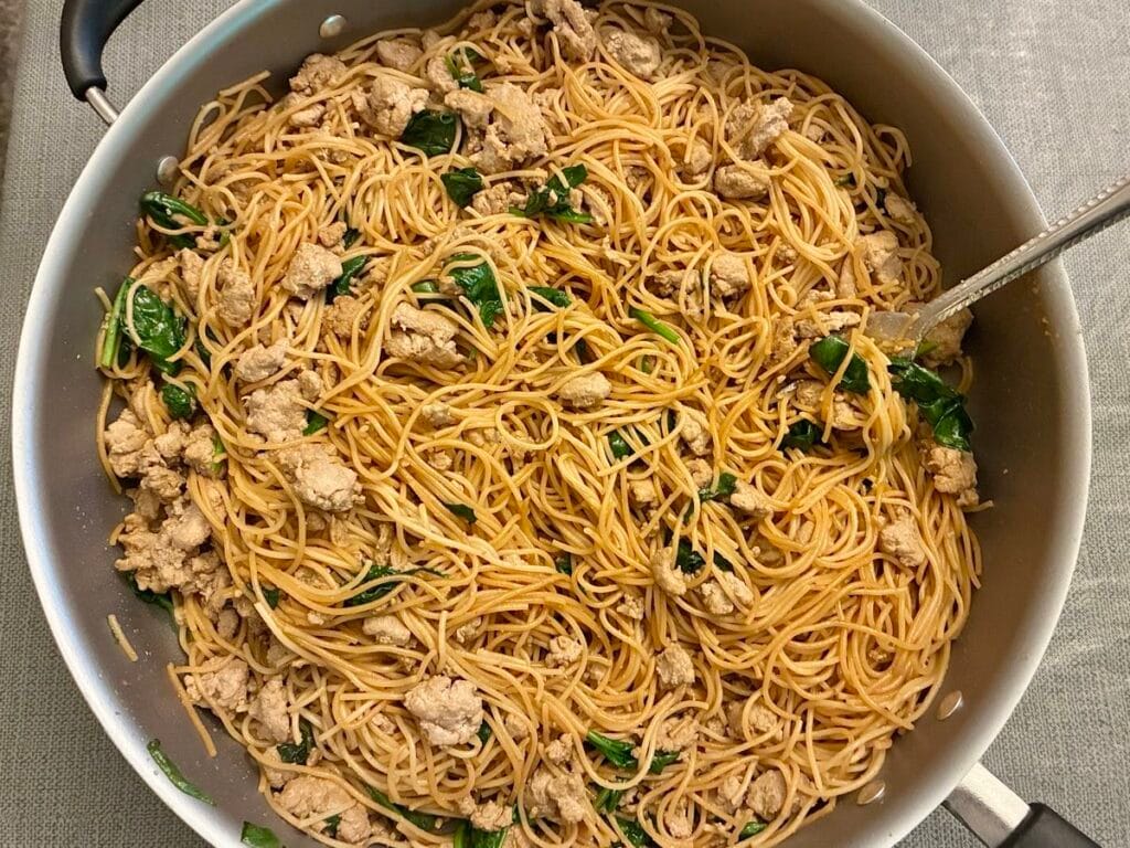 15-Minute Ground Turkey Garlic Noodles (Easy Asian-Inspired Recipe) 4 A completed dish of ground turkey garlic noodles and fresh wilted spinach inside a large skillet.