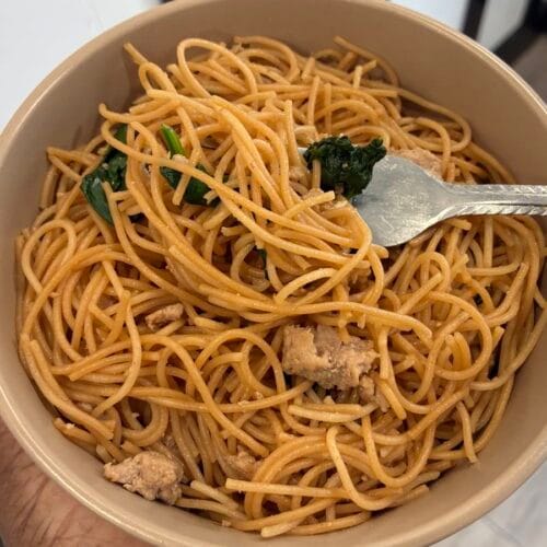 15-Minute Ground Turkey Garlic Noodles (Easy Asian-Inspired Recipe) 5 A unique close up shot of a fork twisting up a mouthful of glossy ground turkey garlic noodles from a serving bowl.