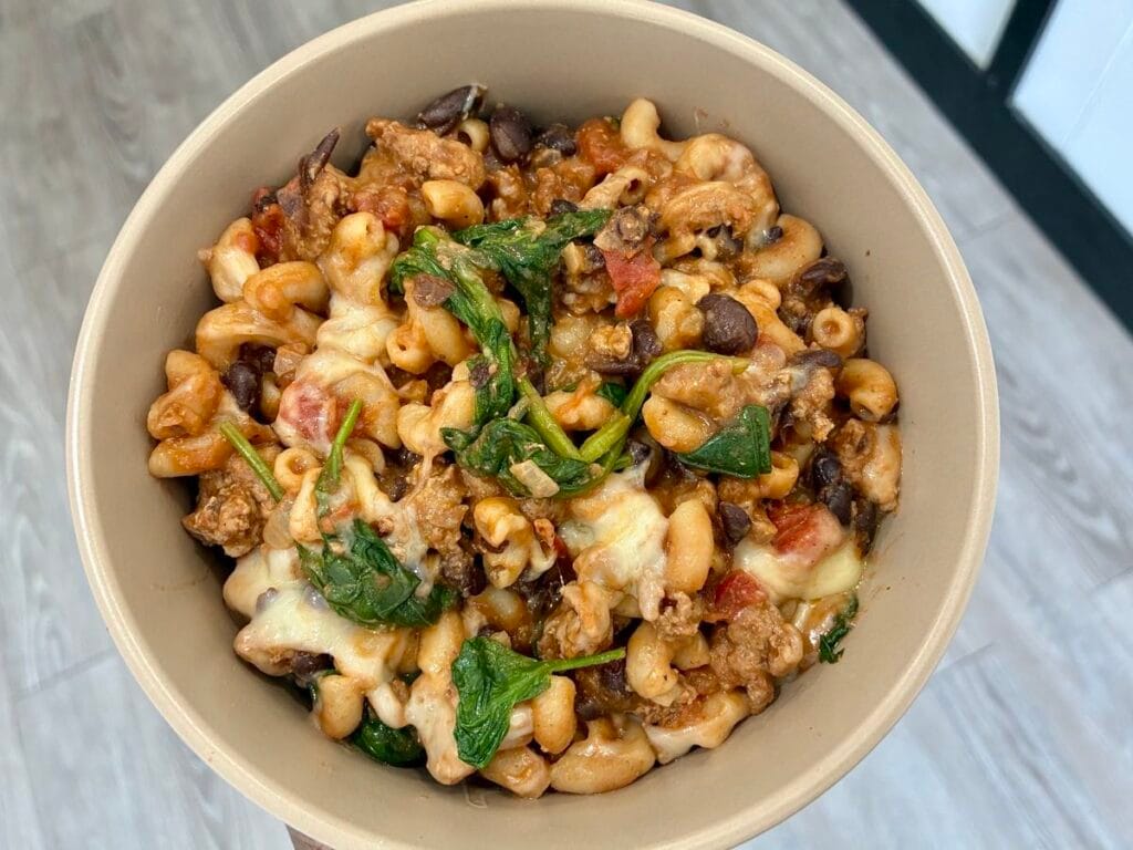 A comforting serving of healthy ground turkey chili mac resting inside a matte stoneware bowl.