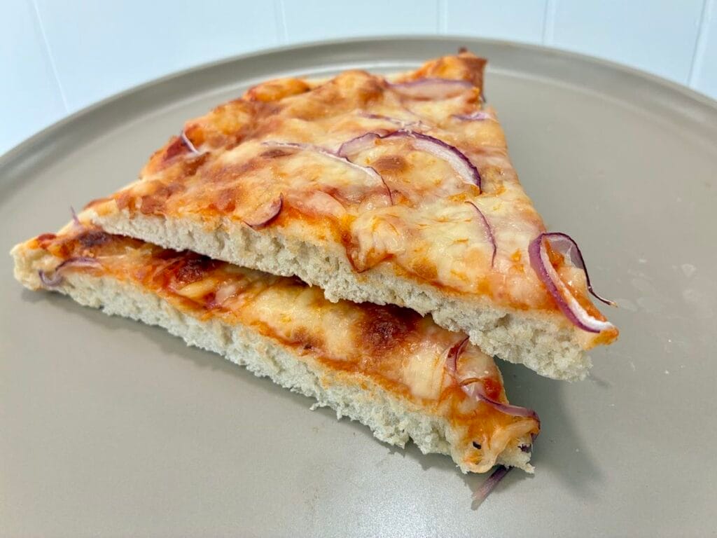 Healthy One-Bowl Artisan Pizza Dough (with An Oat Flour Twist) 2 A side view of a couple of baked pizza slices stacked on top of each other showing the airy internal crumb structure.