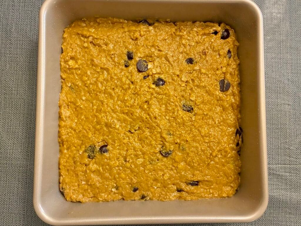 Healthy Eggless Pumpkin Chocolate Chip Snack Cake (8x8 Pan) 5 The completed thick batter for the healthy eggless pumpkin chocolate chip snack cake spread evenly into a square 8x8 inch baking pan, ready for the oven.