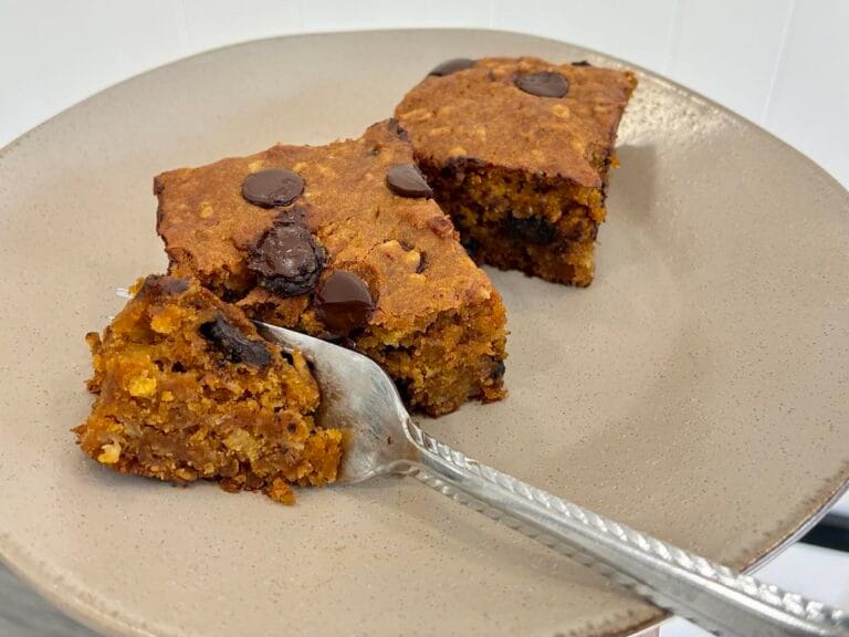 Healthy Eggless Pumpkin Chocolate Chip Snack Cake (8x8 Pan) 1 A close-up shot of a fork slicing into a thick, tender piece of the wholesome eggless pumpkin chocolate chip snack cake made with a twist of quick oats.